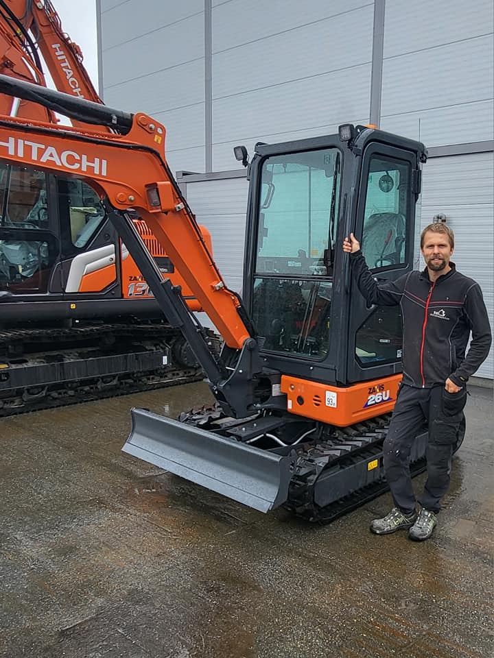 Ansatt hos RS Bygg & Maskin AS ved siden av en minigraver